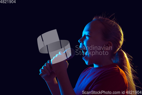 Image of Caucasian girl\'s portrait isolated on dark studio background in neon light