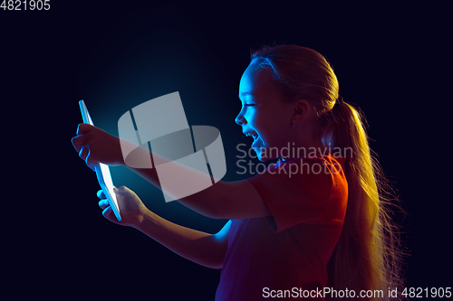 Image of Caucasian girl\'s portrait isolated on dark studio background in neon light