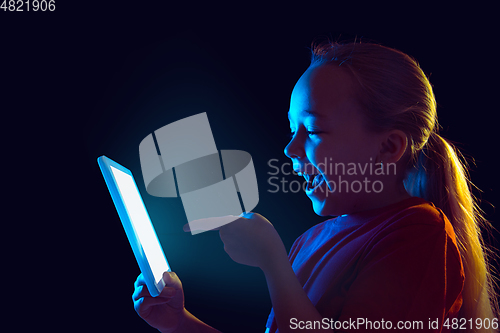 Image of Caucasian girl\'s portrait isolated on dark studio background in neon light