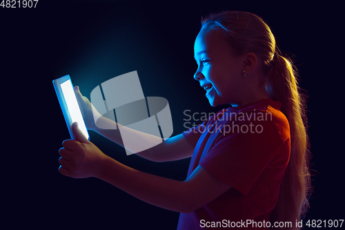 Image of Caucasian girl\'s portrait isolated on dark studio background in neon light