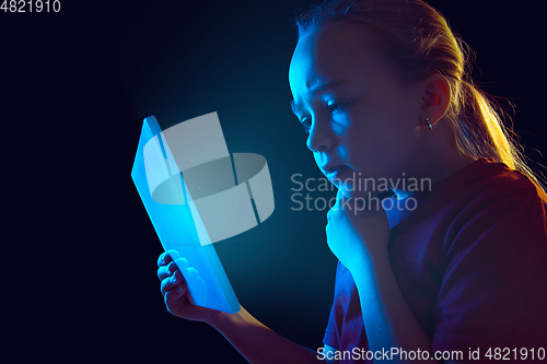 Image of Caucasian girl\'s portrait isolated on dark studio background in neon light