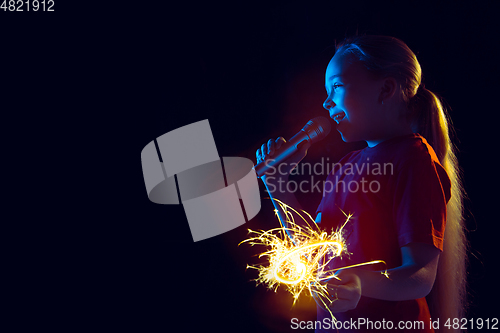 Image of Caucasian girl\'s portrait isolated on dark studio background in neon light