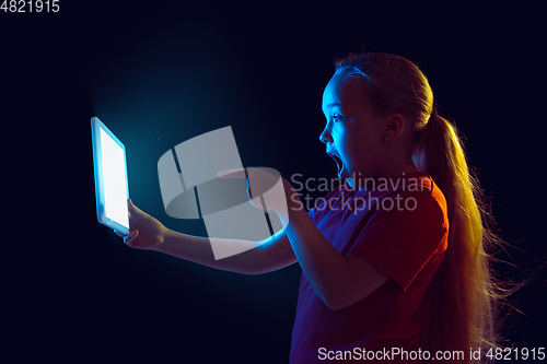 Image of Caucasian girl\'s portrait isolated on dark studio background in neon light