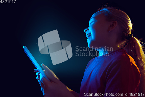 Image of Caucasian girl\'s portrait isolated on dark studio background in neon light