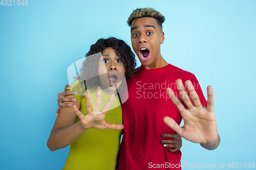 Image of Young emotional african-american man and woman on blue background