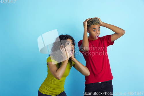 Image of Young emotional african-american man and woman on blue background