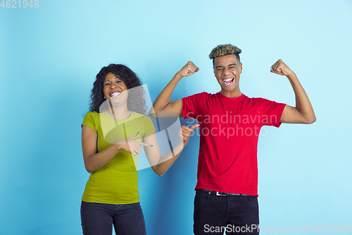 Image of Young emotional african-american man and woman on blue background