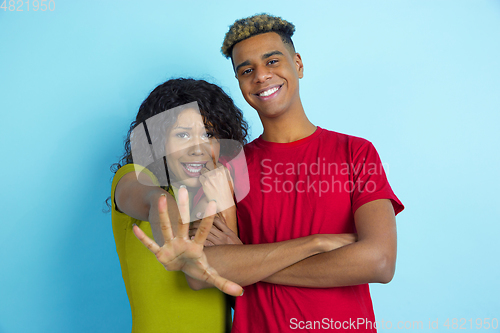 Image of Young emotional african-american man and woman on blue background