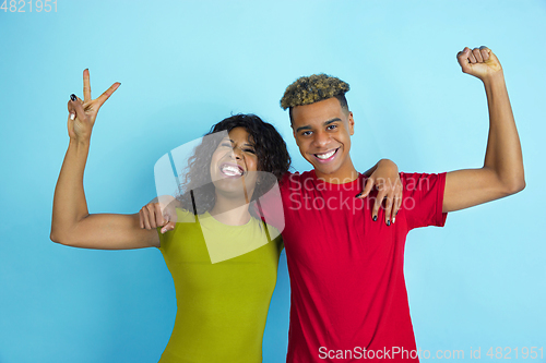 Image of Young emotional african-american man and woman on blue background