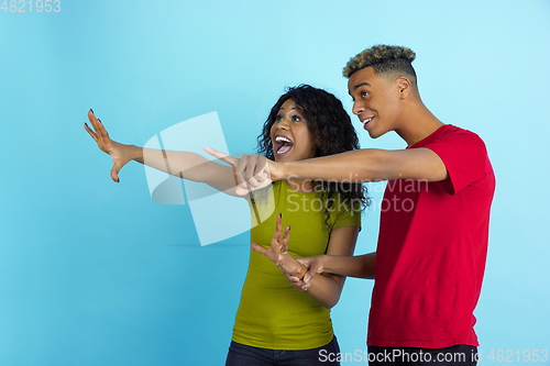 Image of Young emotional african-american man and woman on blue background