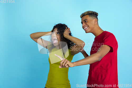 Image of Young emotional african-american man and woman on blue background