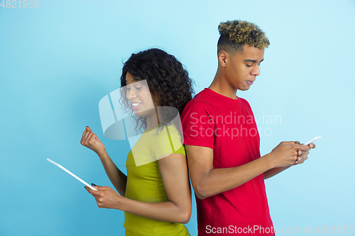 Image of Young emotional african-american man and woman on blue background