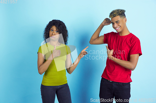 Image of Young emotional african-american man and woman on blue background