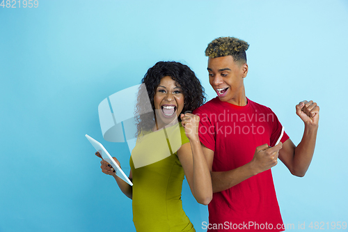 Image of Young emotional african-american man and woman on blue background