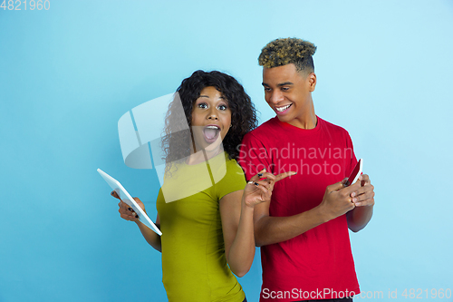 Image of Young emotional african-american man and woman on blue background