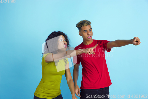 Image of Young emotional african-american man and woman on blue background