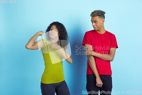 Image of Young emotional african-american man and woman on blue background