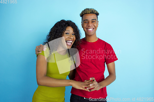 Image of Young emotional african-american man and woman on blue background