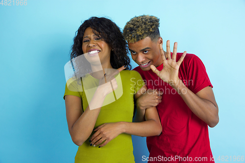 Image of Young emotional african-american man and woman on blue background