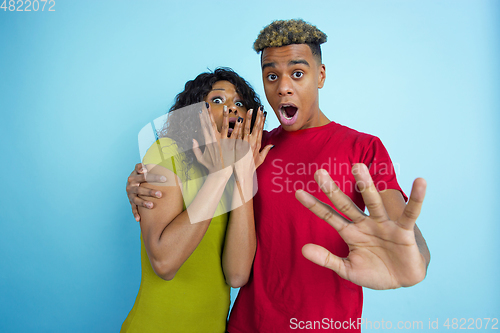 Image of Young emotional african-american man and woman on blue background