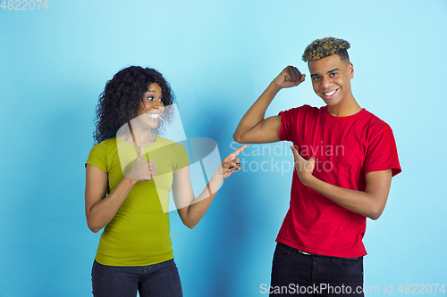 Image of Young emotional african-american man and woman on blue background