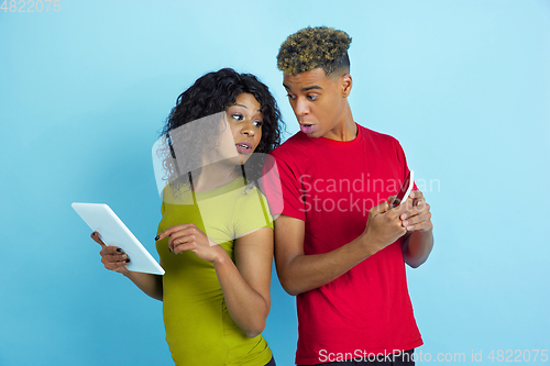 Image of Young emotional african-american man and woman on blue background