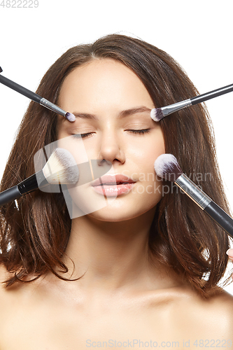 Image of beautiful girl with makeup brushes