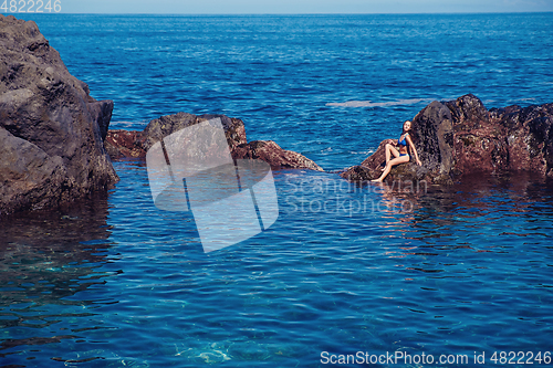 Image of beautiful girl resting in natural ocean swimming pool