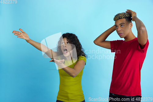 Image of Young emotional african-american man and woman on blue background