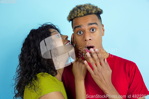 Image of Young emotional african-american man and woman on blue background