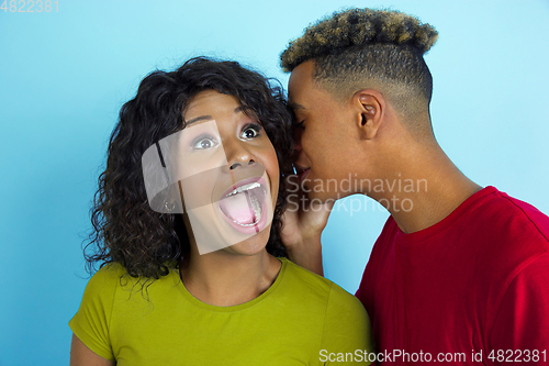 Image of Young emotional african-american man and woman on blue background