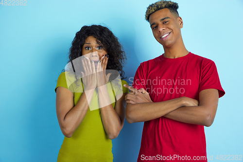 Image of Young emotional african-american man and woman on blue background