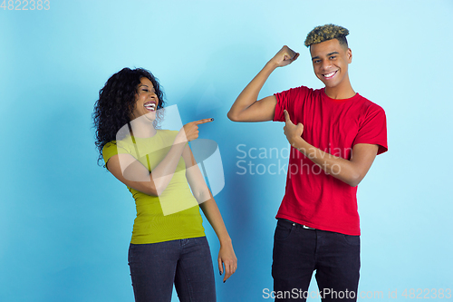 Image of Young emotional african-american man and woman on blue background