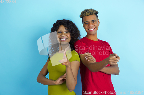 Image of Young emotional african-american man and woman on blue background