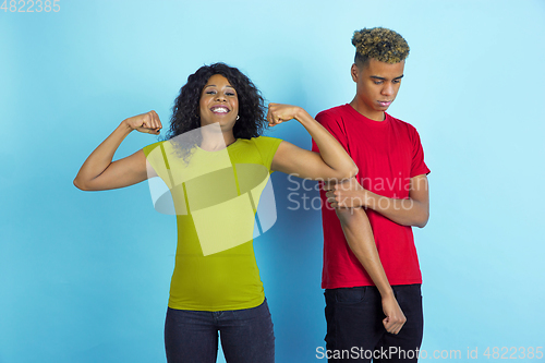 Image of Young emotional african-american man and woman on blue background