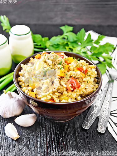 Image of Barley porridge with minced meat in bowl on dark wooden board