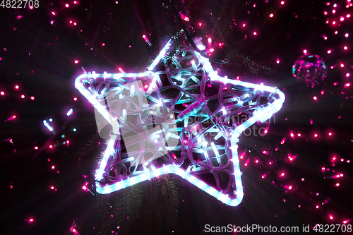 Image of Bright beautiful glowing star on a Christmas tree in the evening