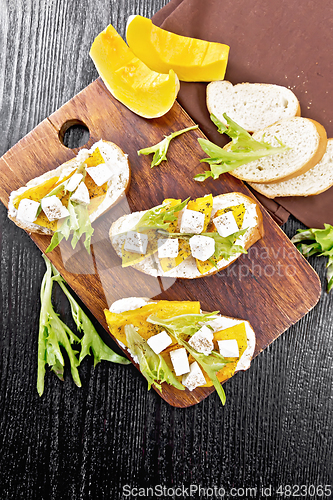 Image of Bruschetta with pumpkin and arugula on black board top