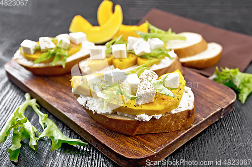 Image of Bruschetta with pumpkin and arugula on board