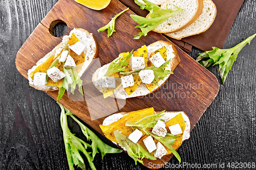 Image of Bruschetta with pumpkin and arugula on wooden board top