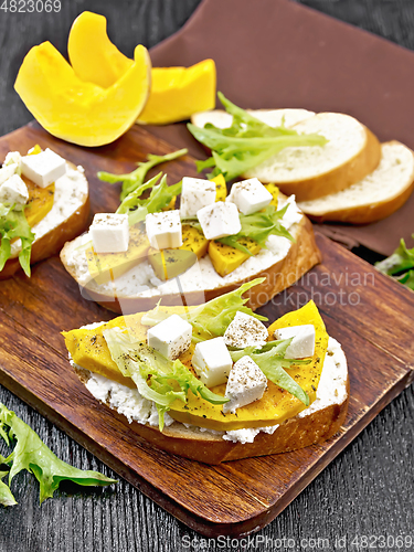 Image of Bruschetta with pumpkin and arugula on wooden board