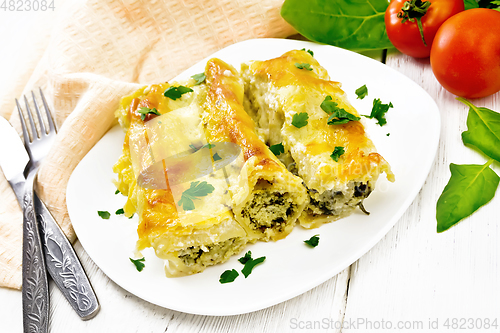 Image of Cannelloni with curd and spinach in plate on white board