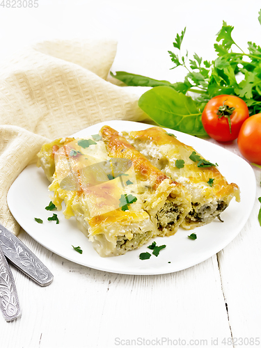 Image of Cannelloni with curd and spinach in plate on wooden board