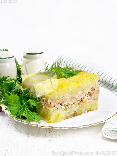 Image of Casserole with potatoes and fish in plate on light table