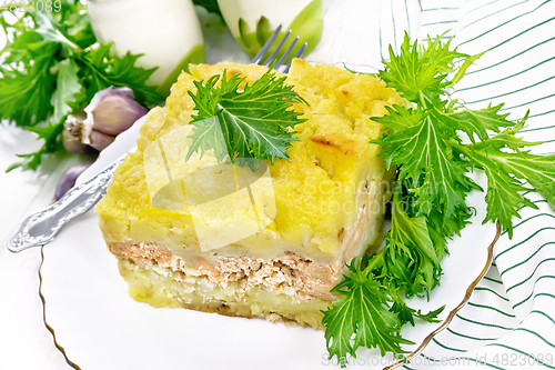 Image of Casserole with potatoes and fish in plate on white wooden board