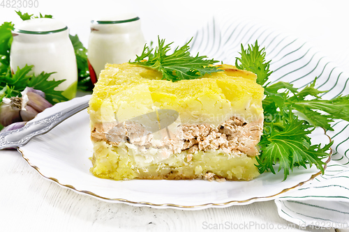 Image of Casserole with potatoes and fish in plate on wooden board