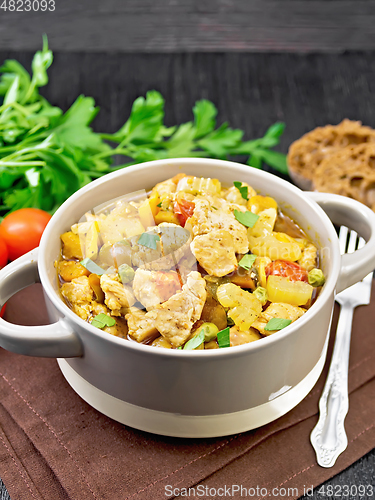 Image of Chicken with vegetables and peas in saucepan on black board