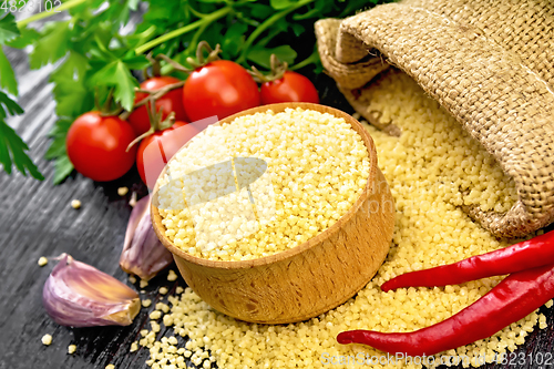 Image of Couscous raw in bowl on dark wooden board