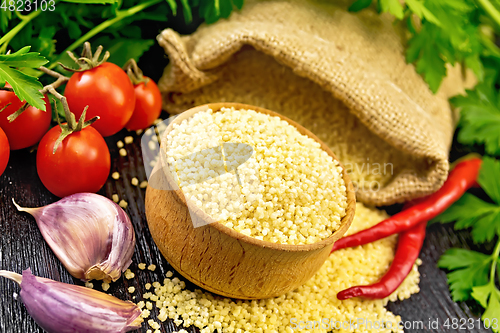 Image of Couscous raw in bowl on wooden board