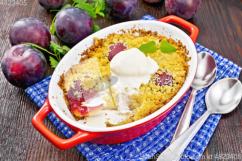 Image of Crumble with plum and ice cream in brazier on dark board